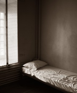 An empty prison cell with a bed in it.