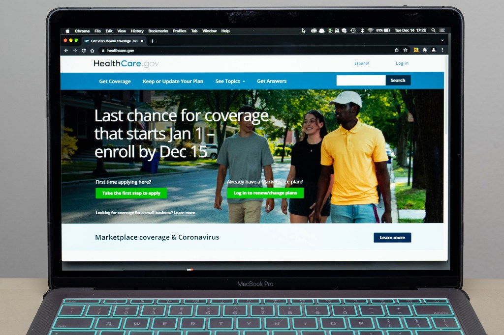 A photograph of a laptop. On the screen is the homepage for healthcare.gov.