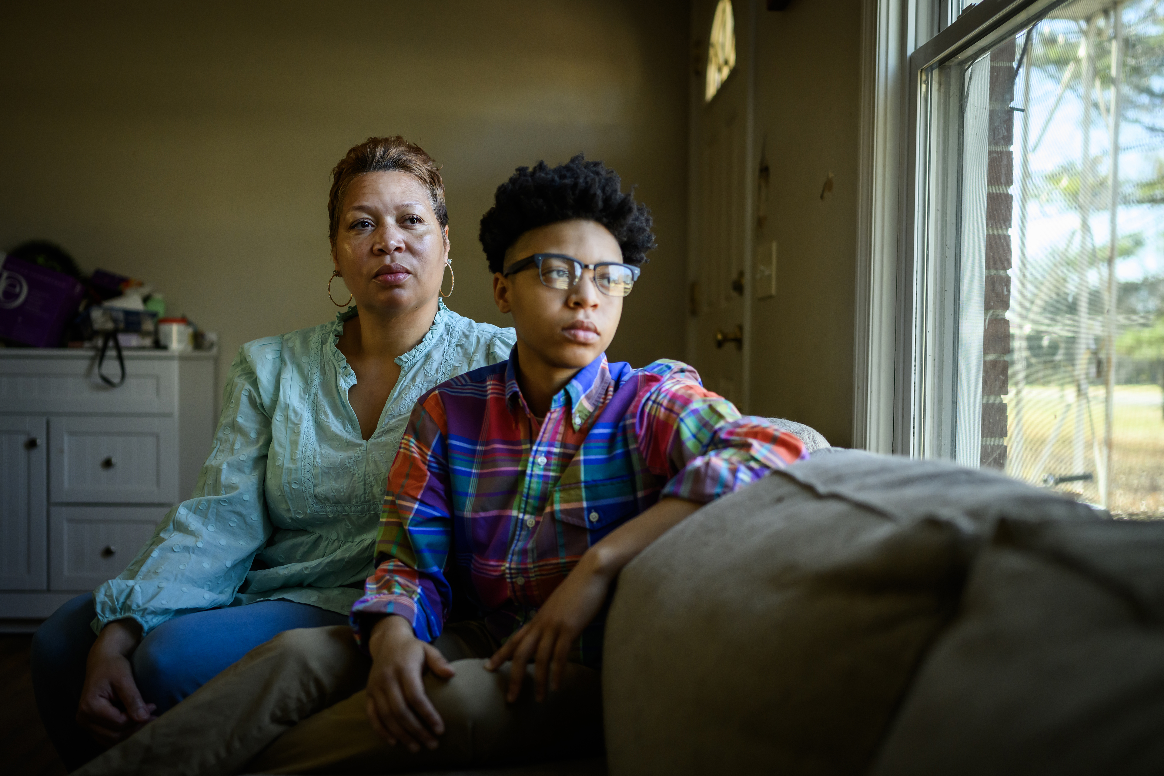 DiJuana Davis and her child Treasure Woodard sit on a couch in their home.