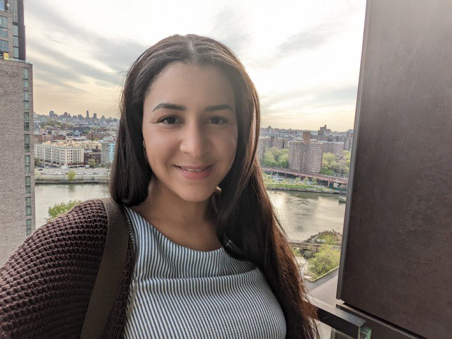 A selfie portrait of Diana Perez. She is outside on a balcony in New York City.