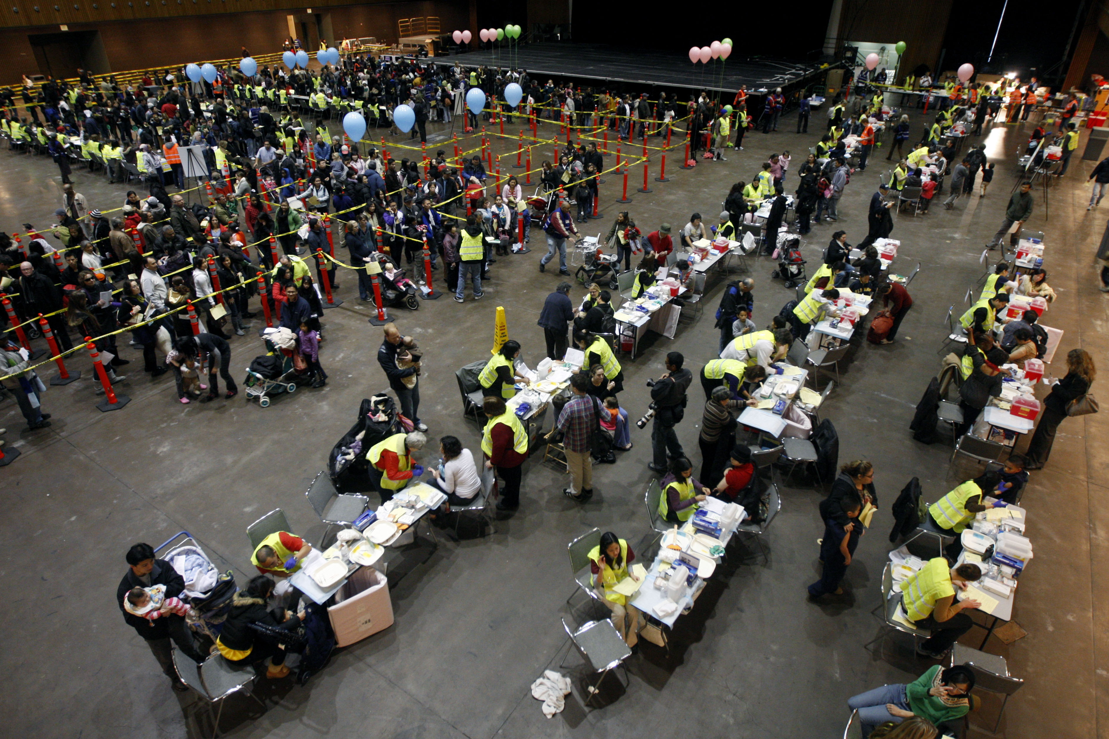 An areal view of a large-scale vaccination set up in a warehouse-like room.