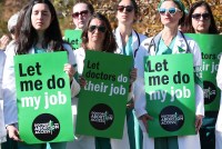 A crowd of doctors hold signs that say, "let me do my job" and "let doctors do their job / doctors for abortion access."