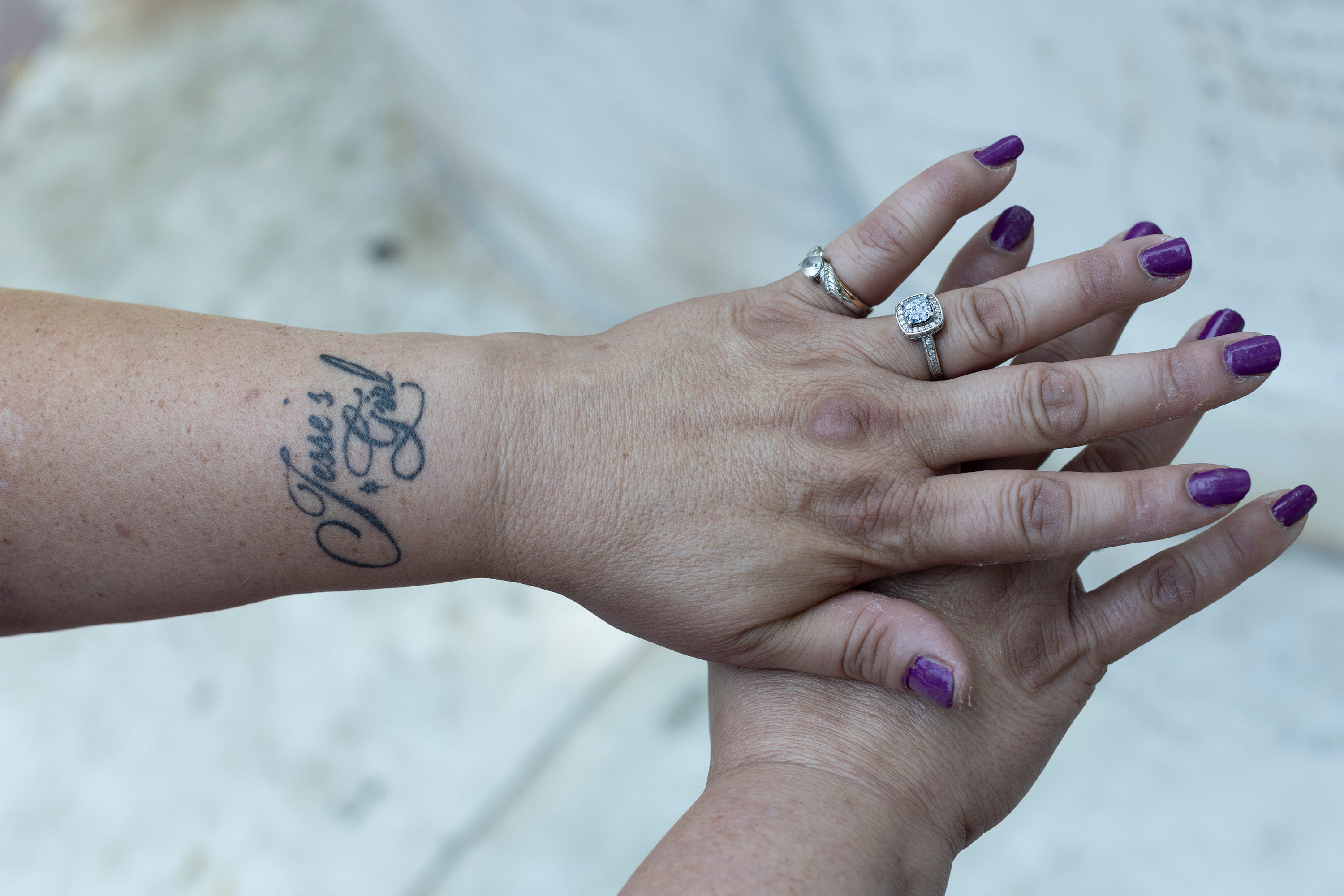 A photo of Sonja Verdugo's hands. She wears rings on her left hand and has a tattoo that reads, "Jesse's girl."