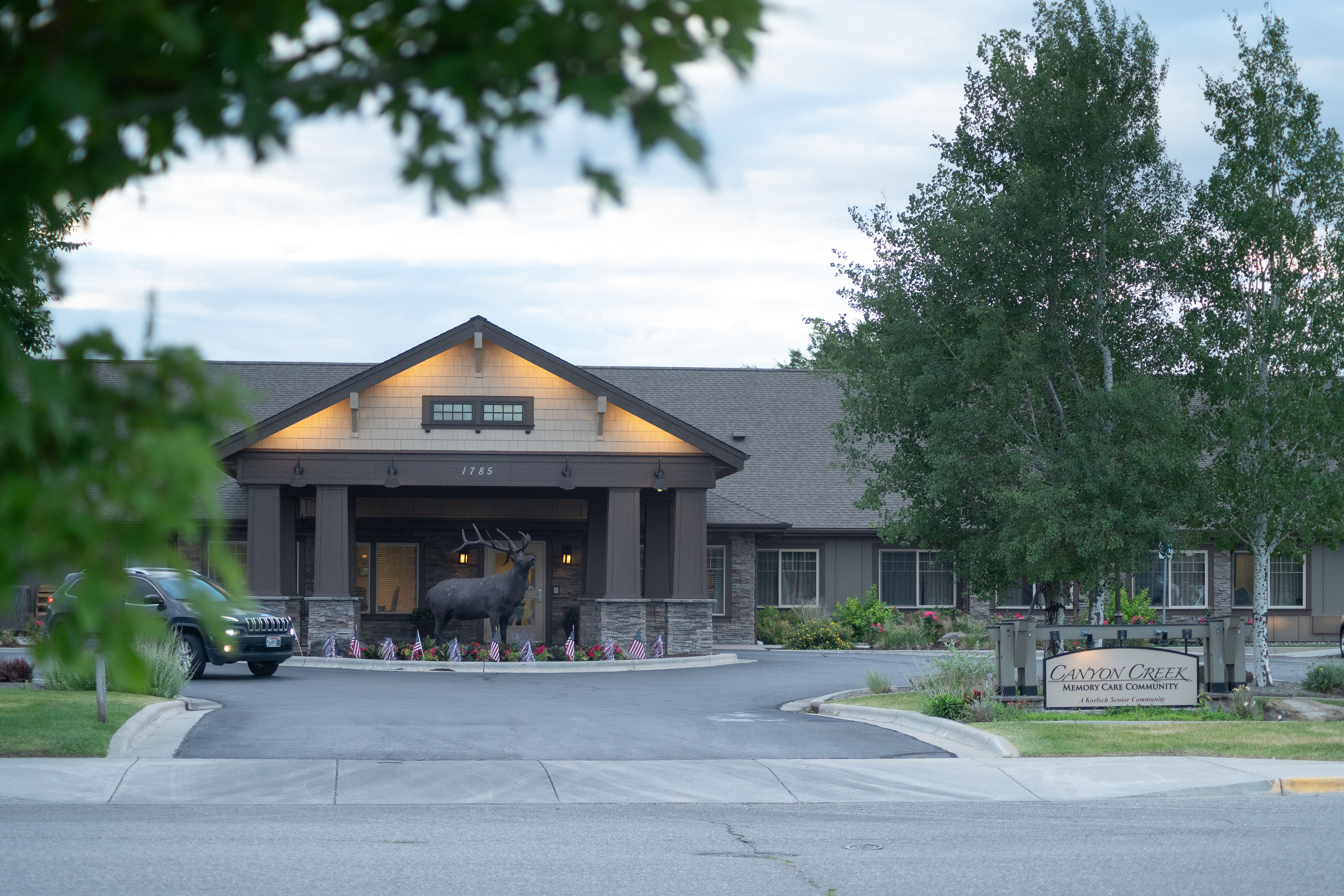 An exterior photograph of Canyon Creek Memory Care Community in Billings, MT. July 2nd, 2024. There is a large statue of a moose out front.