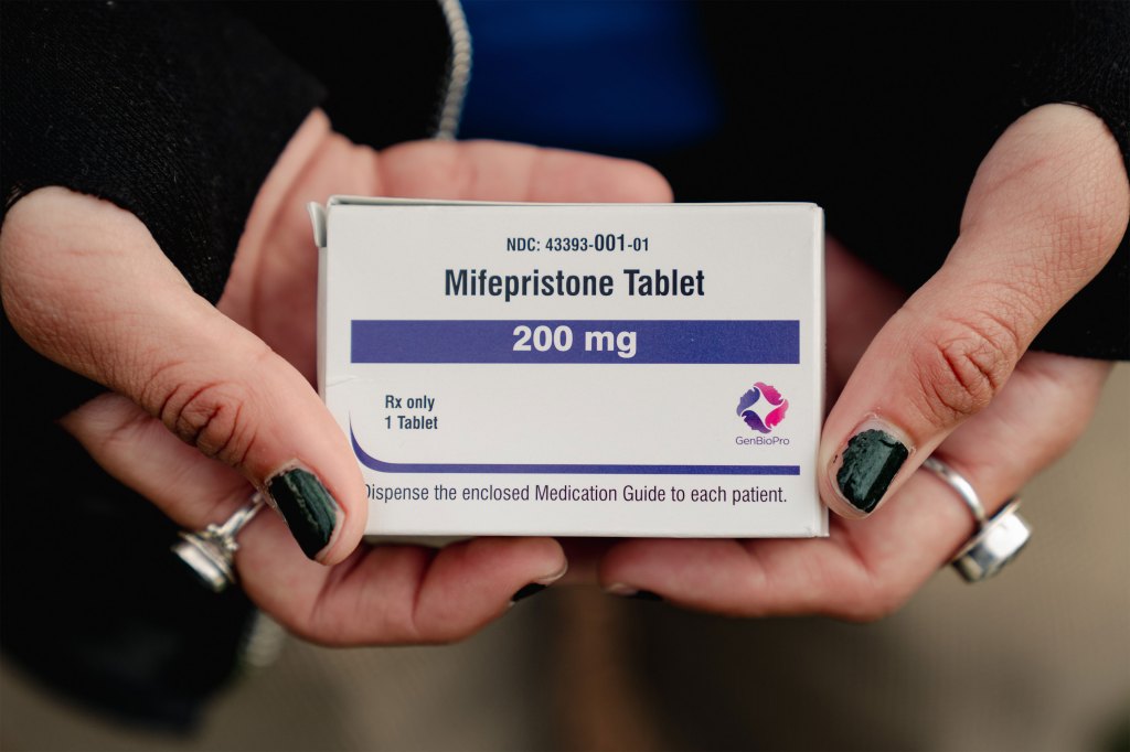 A person holds a box of mifepristone in their hands.