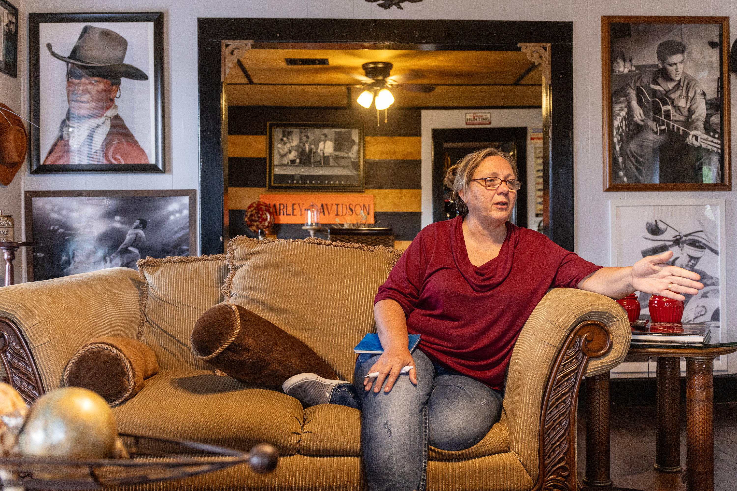 A photo of a woman sitting on a couch and speaking to someone out of view.