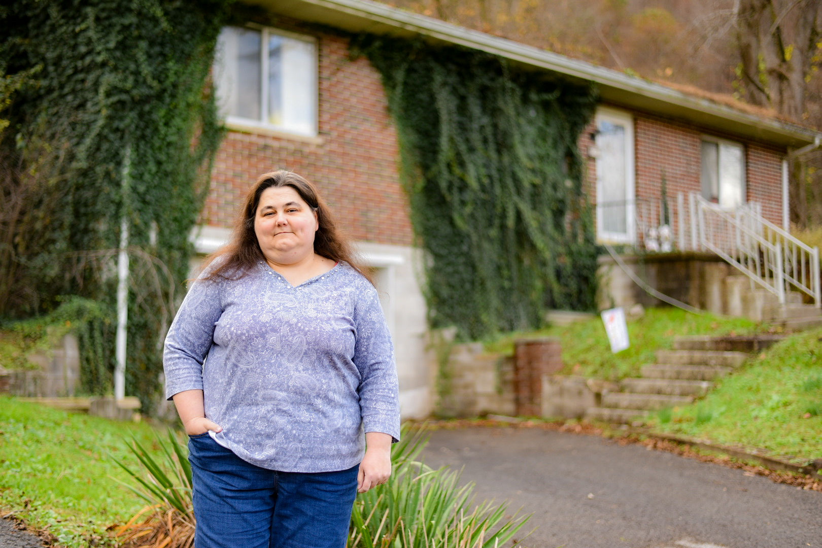 A photo of a woman standing for a photo outside of her home.