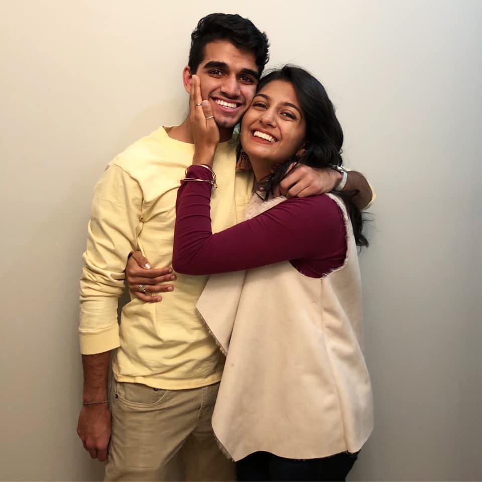 A photo of a brother and sister, both adults, embracing and smiling for the camera.