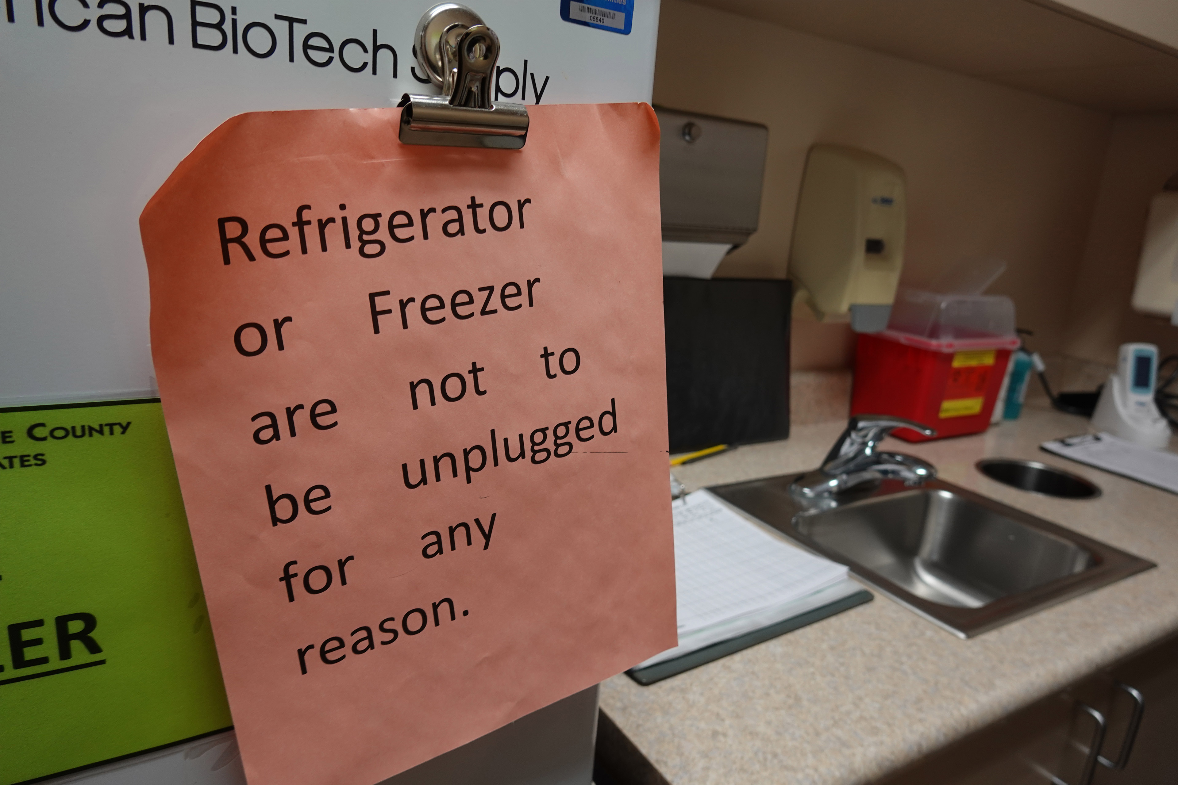 A photo of a note attached to a vaccine fridge that reads, "Refrigerator or freezer are not to be unplugged for any reason."