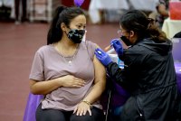 A pregnant woman wearing a face mask received a shot in the arm from a nurse.