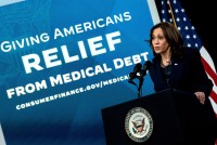 A photo of Kamala Harris speaking at a podium. Behind her is a large backdrop that reads "Giving Americans Relief From Medical Debt."