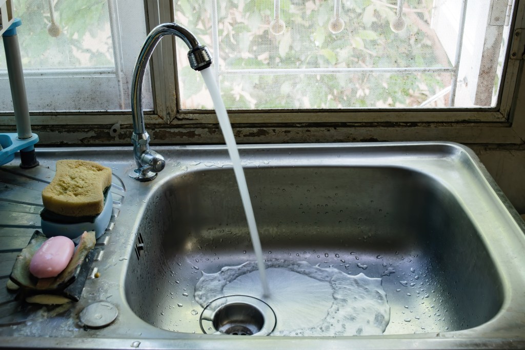 A photo of a kitchen faucet running.