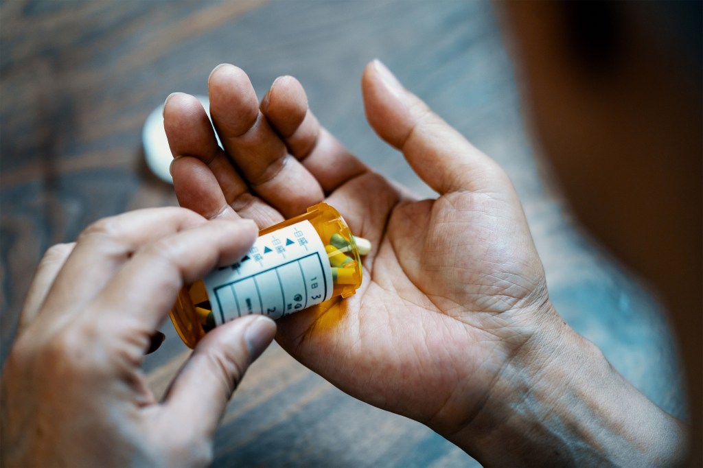 A photo of a man pouring pills into his hand.