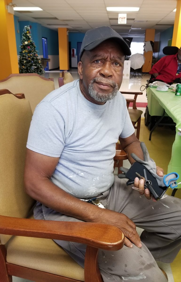 A man in a cap and tshirt is seated on a chair