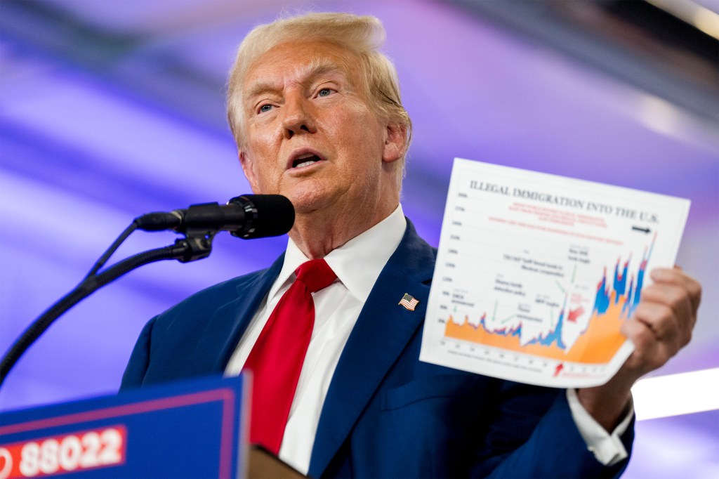 A photo of Trump speaking at a podium, holding up a printed chart about illegal immigration.