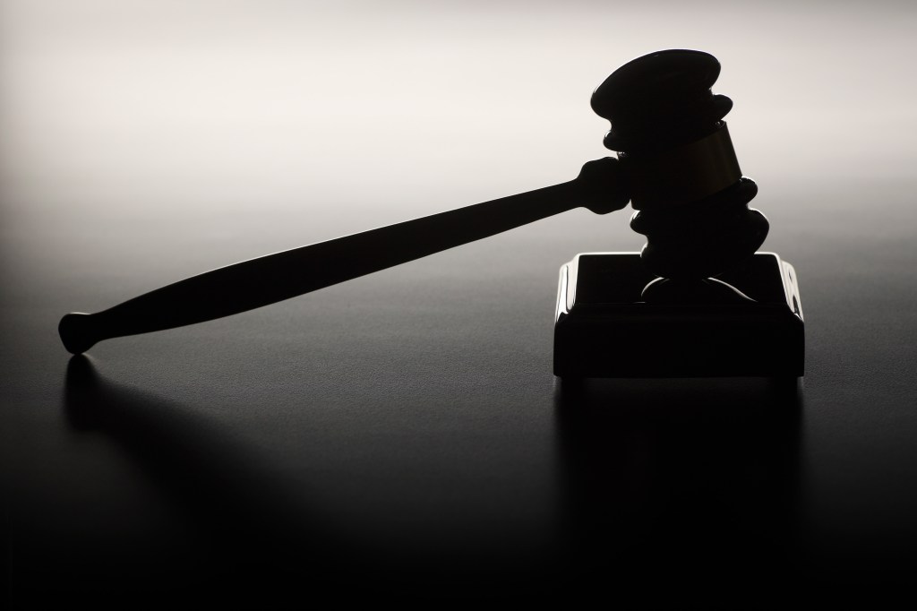 A photo of a gavel resting on its block in silhouette.