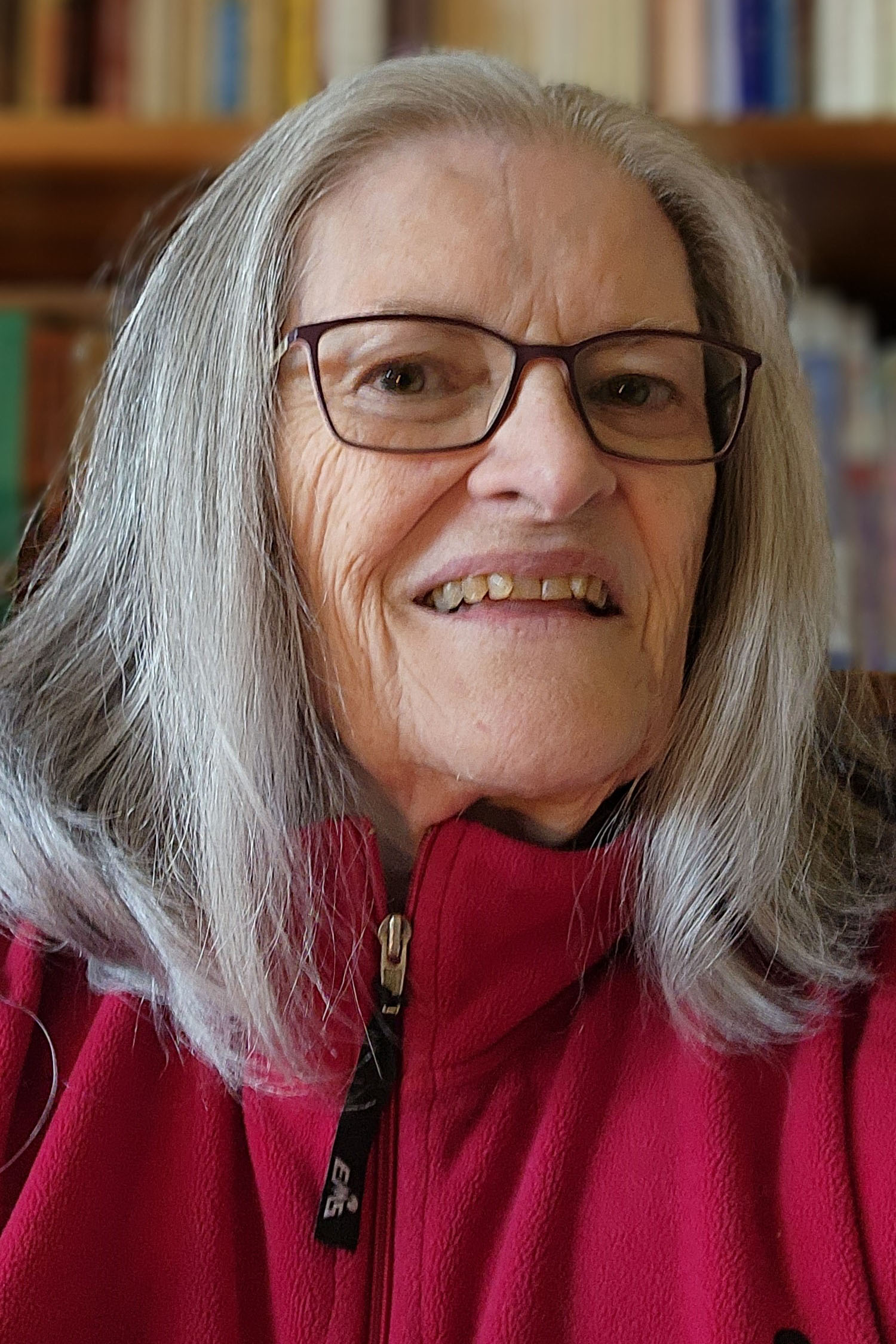 A portrait of Michelle Wallace, a senior woman with shoulder length, straight gray hair and glasses.