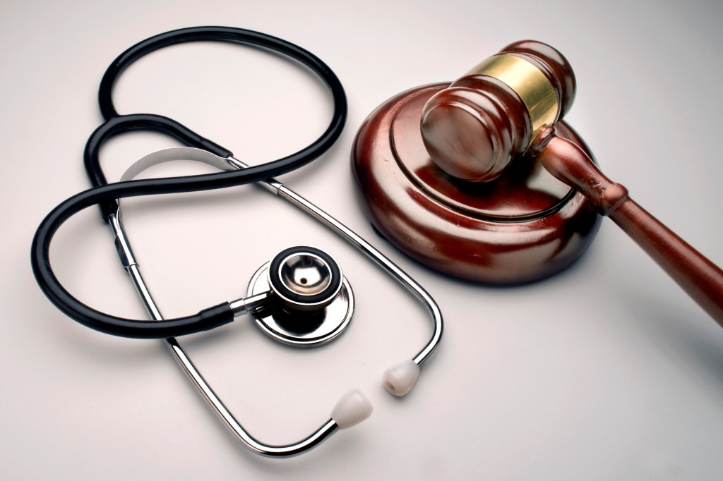 A photo of a gavel and stethoscope on a table.