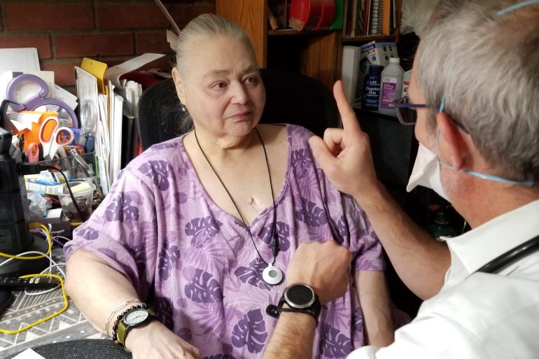 A doctor performs a visual exam on a senior female patient