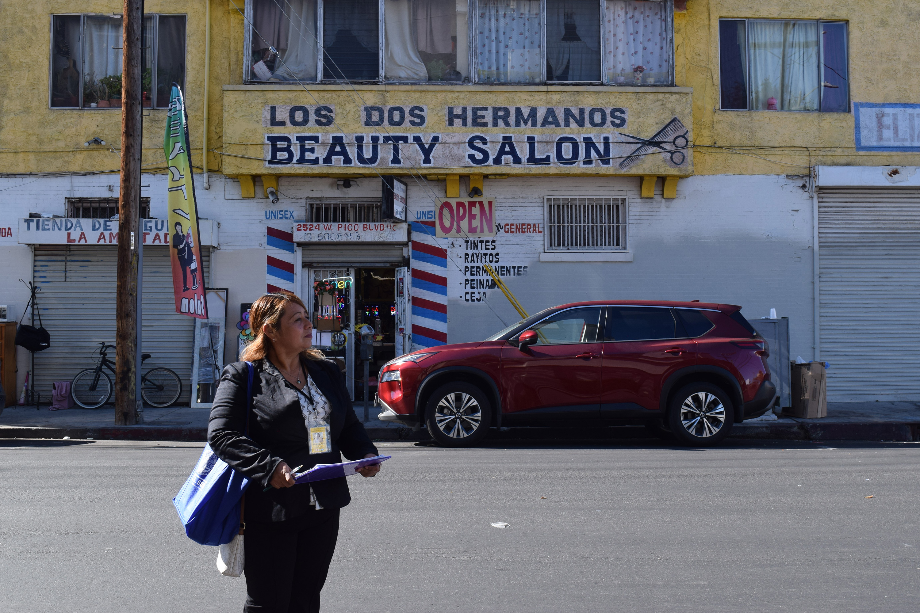 A photo of Yanet Martinez standing outside across the street from a beauty salon.