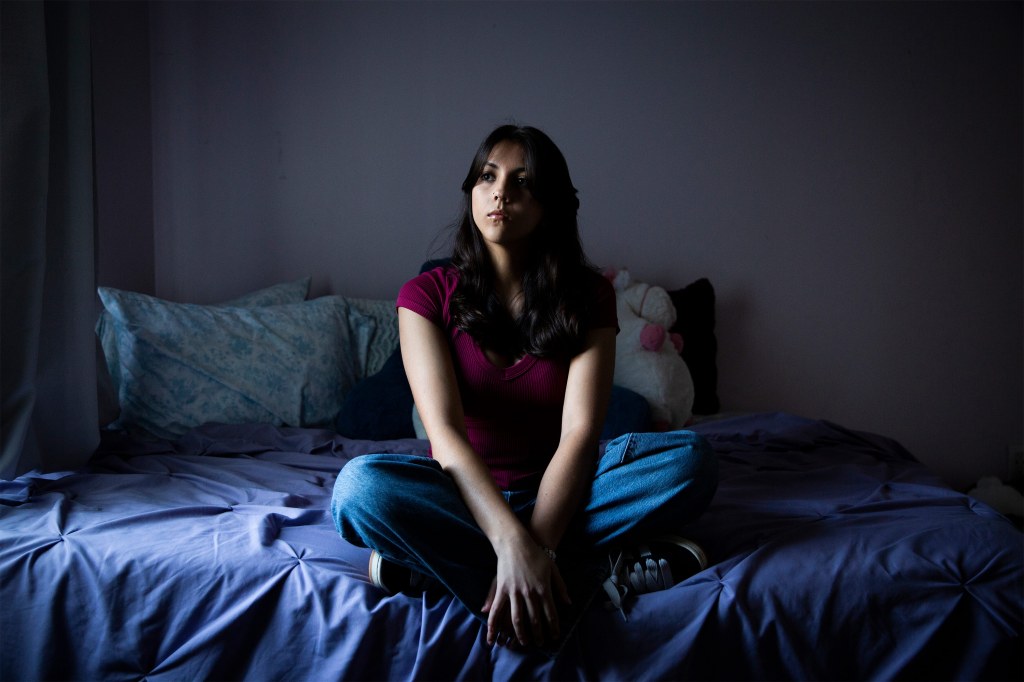 A photo of a teenage girl posing for a portrait in her bedroom.