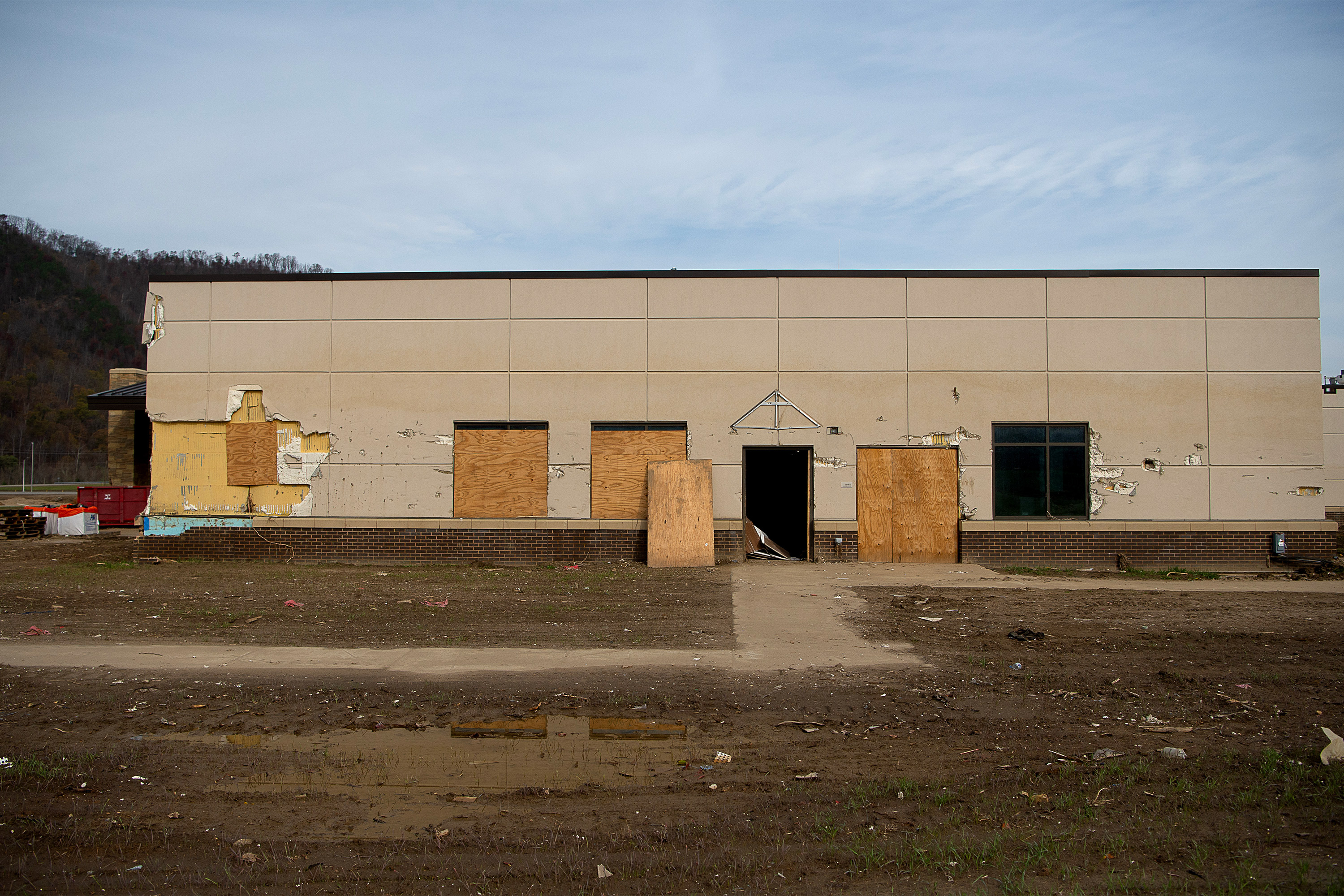 A photo of the front entrance of Unicoi County Hospital. The hospital's sign is torn off and the windows are boarded up.