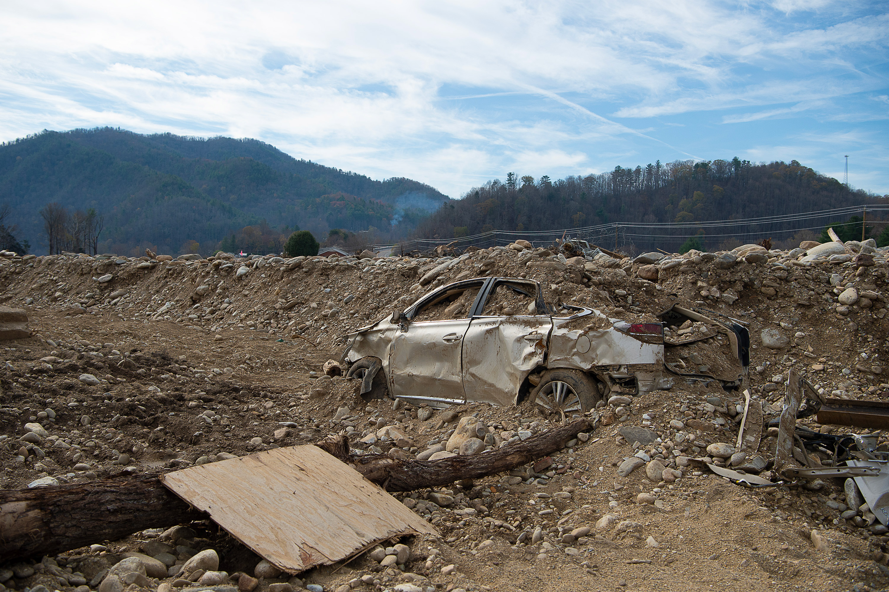 A photo of a car submerged in a deep mound of dirt.