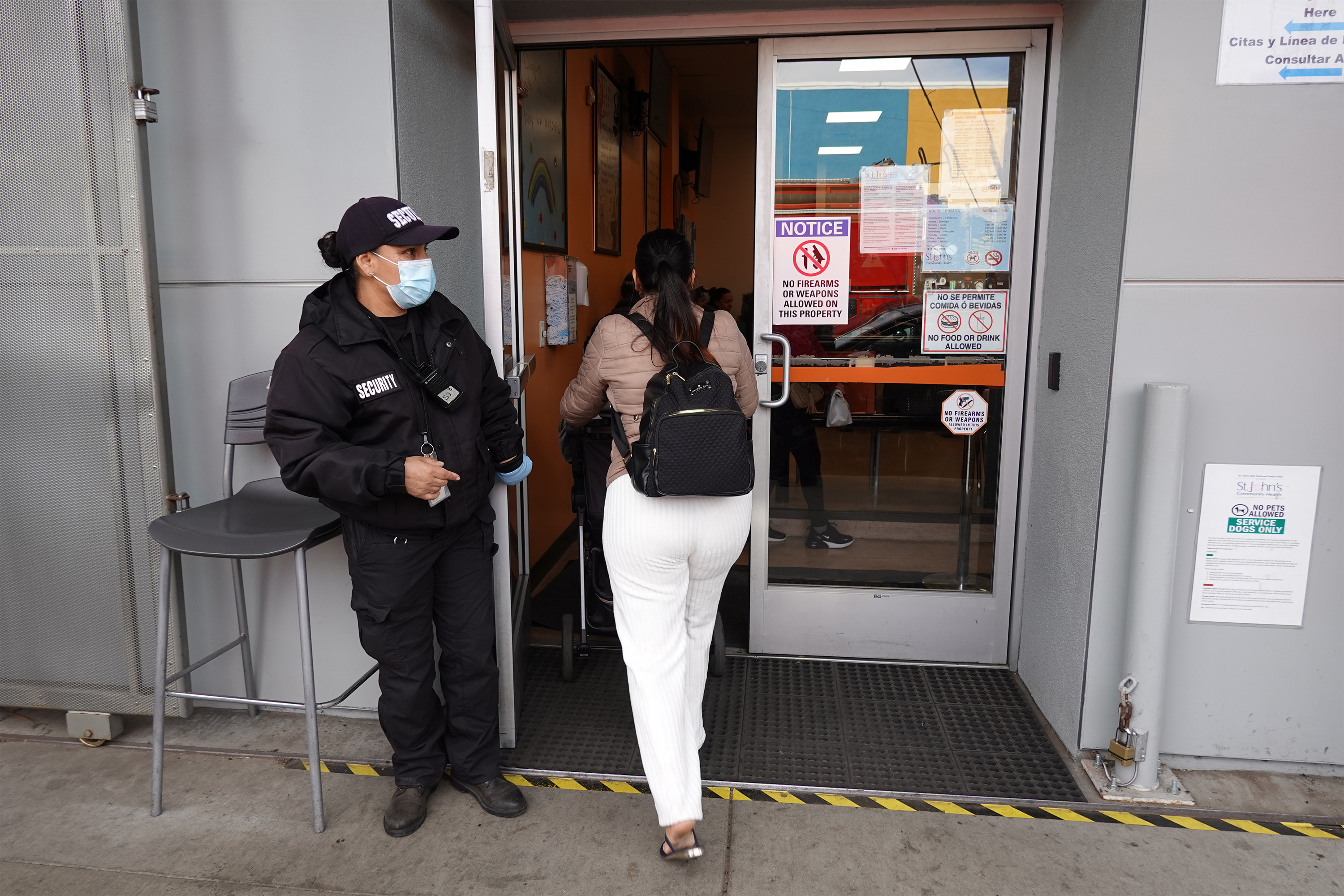 A photo of a security guard letting a woman inside of a clinic.