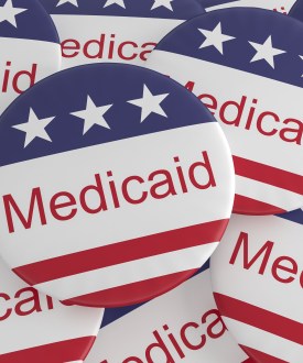 A pile of pins that say "Medicaid" and are decorated with an American flag pattern.