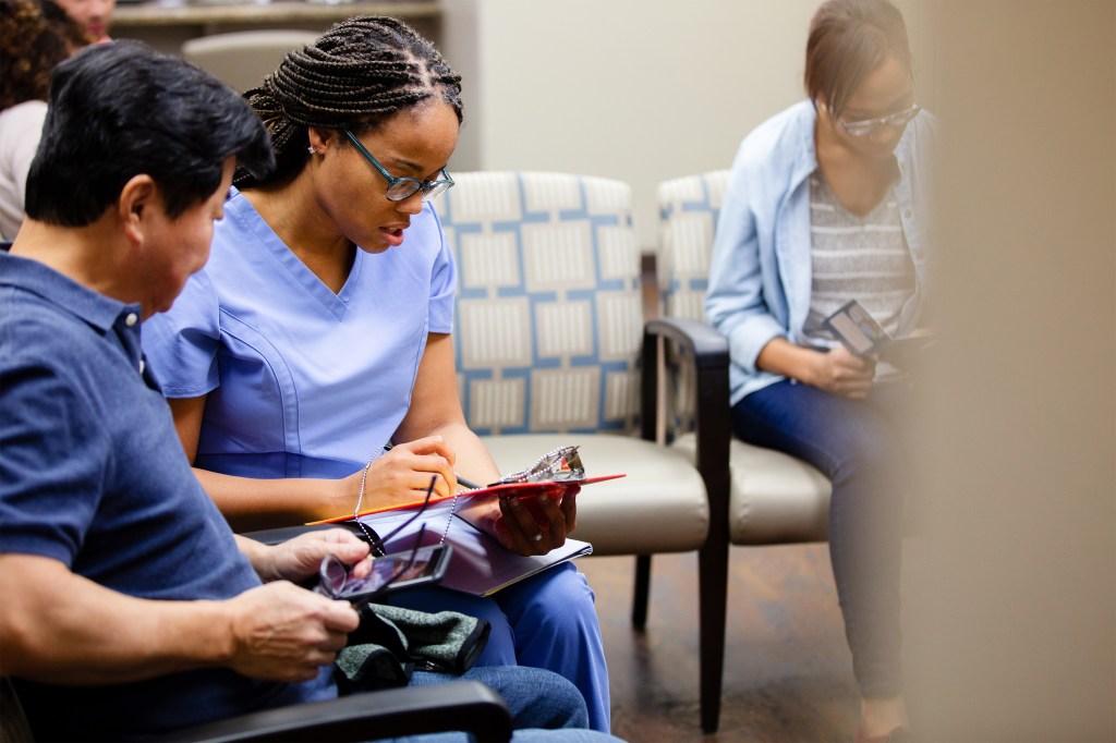 A photo of a nurse talking to a patient in a hospital waiting room.