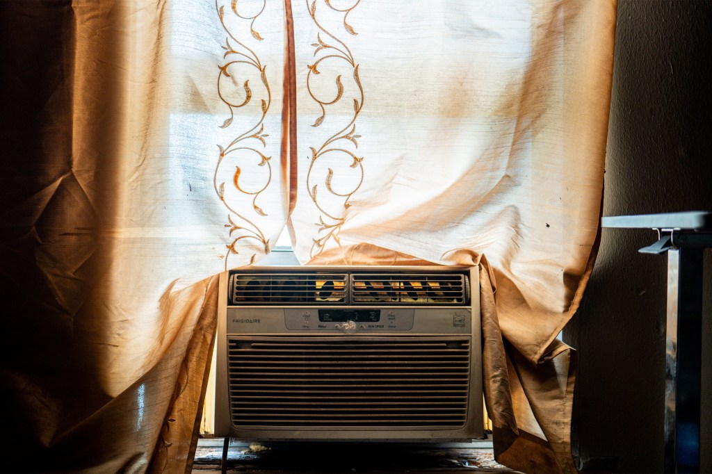 A photo of a window air conditioning unit framed by curtains.