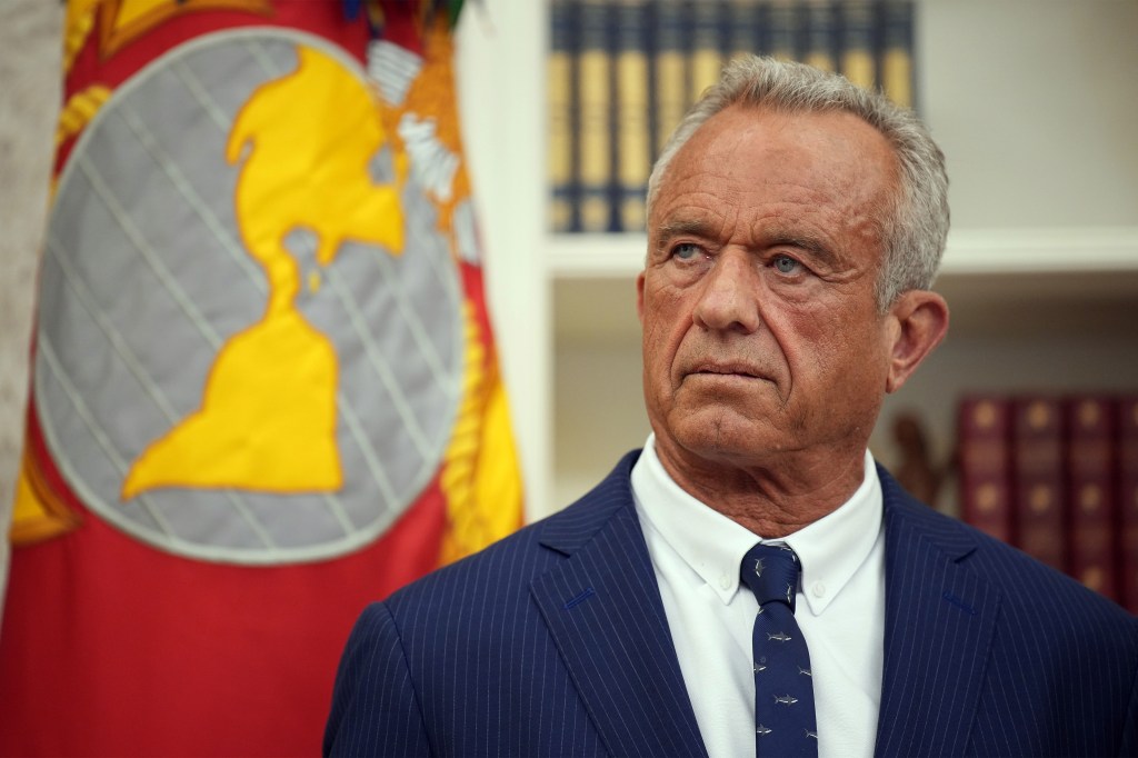 A photo of Robert F. Kennedy Jr. in the Oval Office at the White House. A flag is behind him.