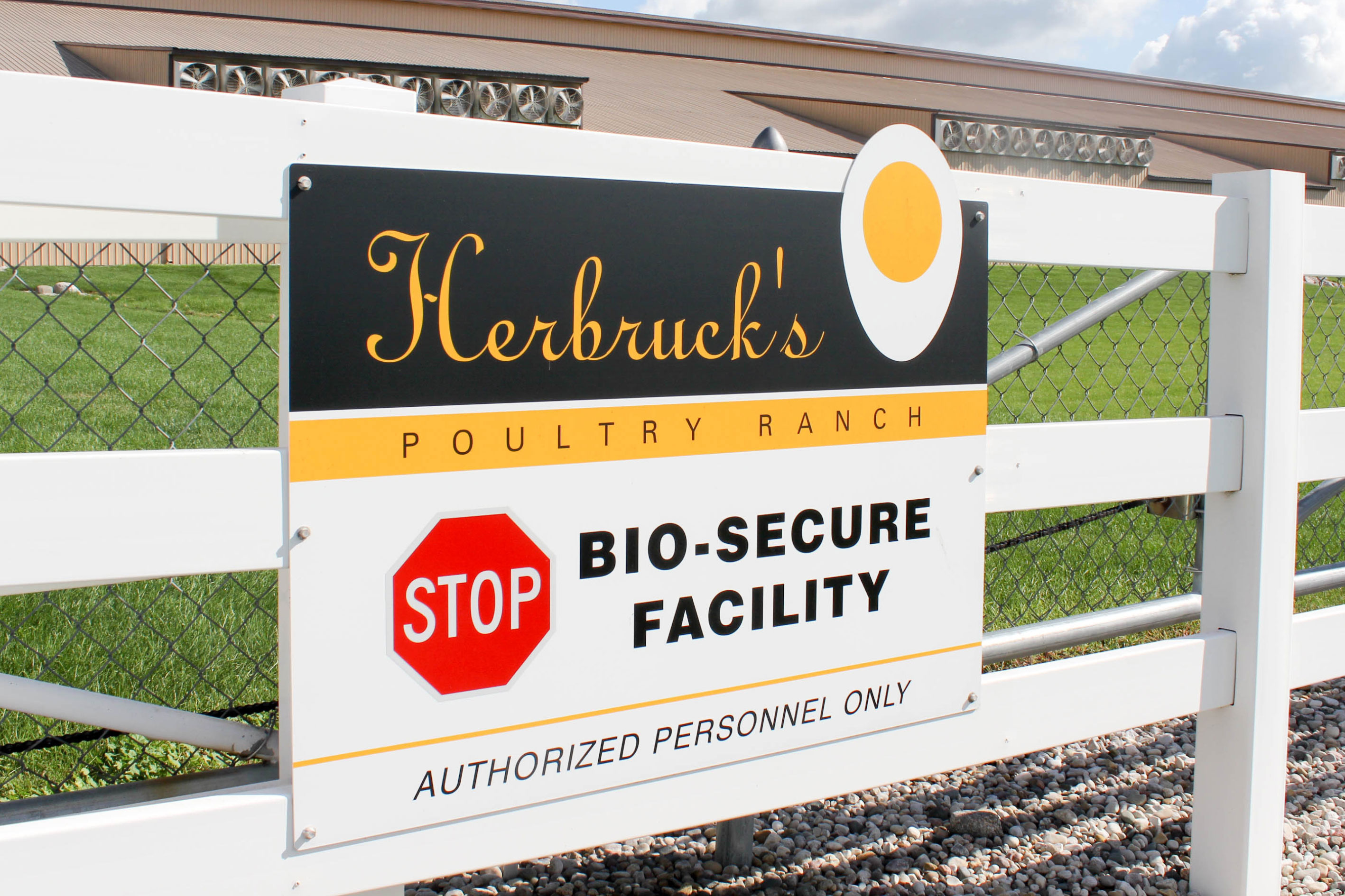 A sign attached to a fence reads "Herbruck's Poultry Ranch. Stop. Bio-secure facility. Authorized Personnel Only."