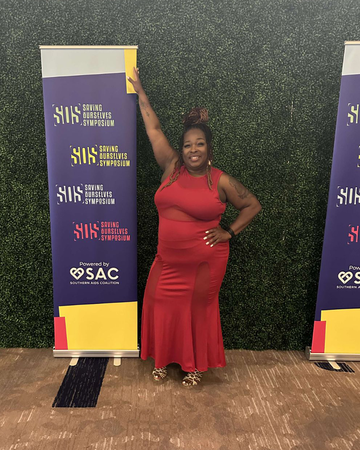 A photo of Latonia Wilkins posing next to a Southern AIDS Coalition banner at an event.