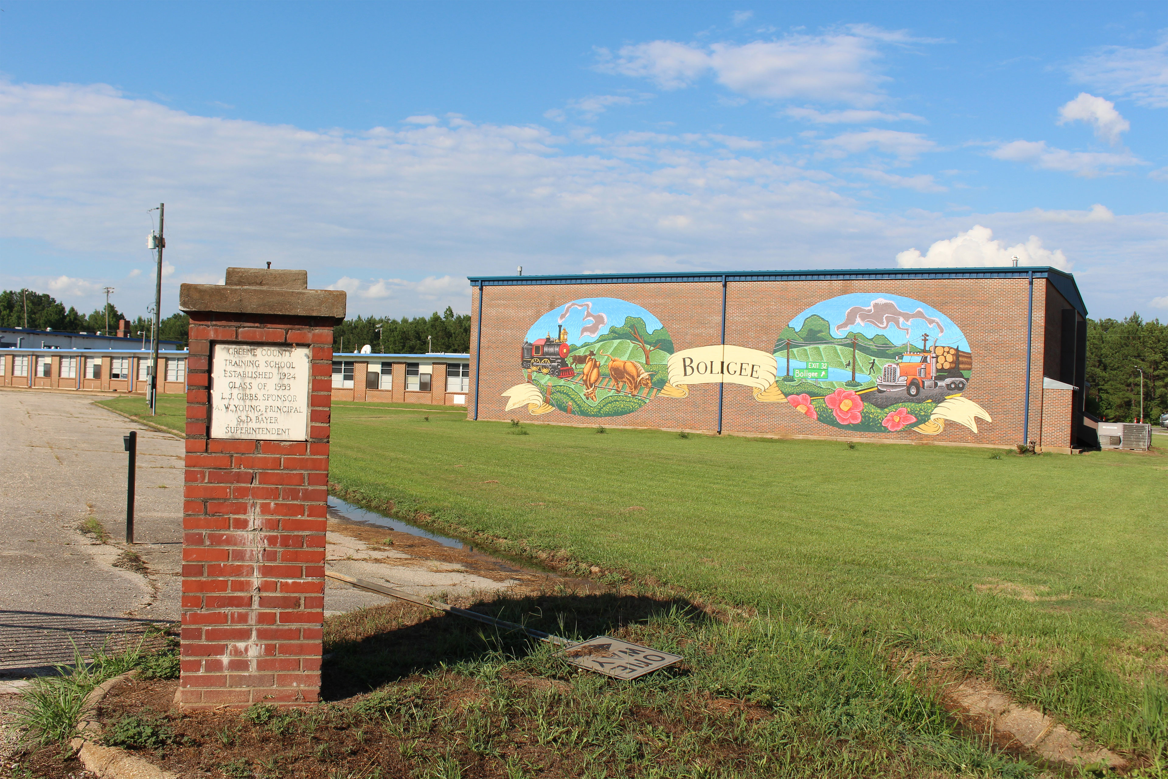 A mural on the side of a building depicts two scenes with "Boligee" painted between the scenes.