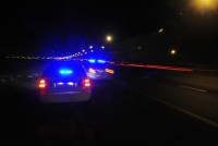 A photo taken at night of two police cars with blue flashing lights driving on a highway.