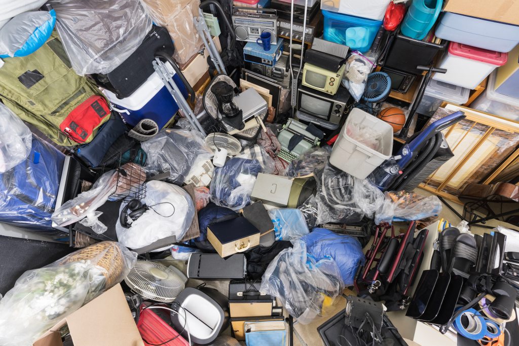 A photo of a large junk pile containing bags of clothing and trash. Home decor, shoes, and vintage electronics are also piled in.