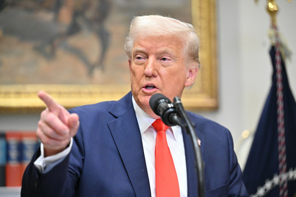 A photo of President Trump at the White House speaking into a microphone, pointing with his hand.