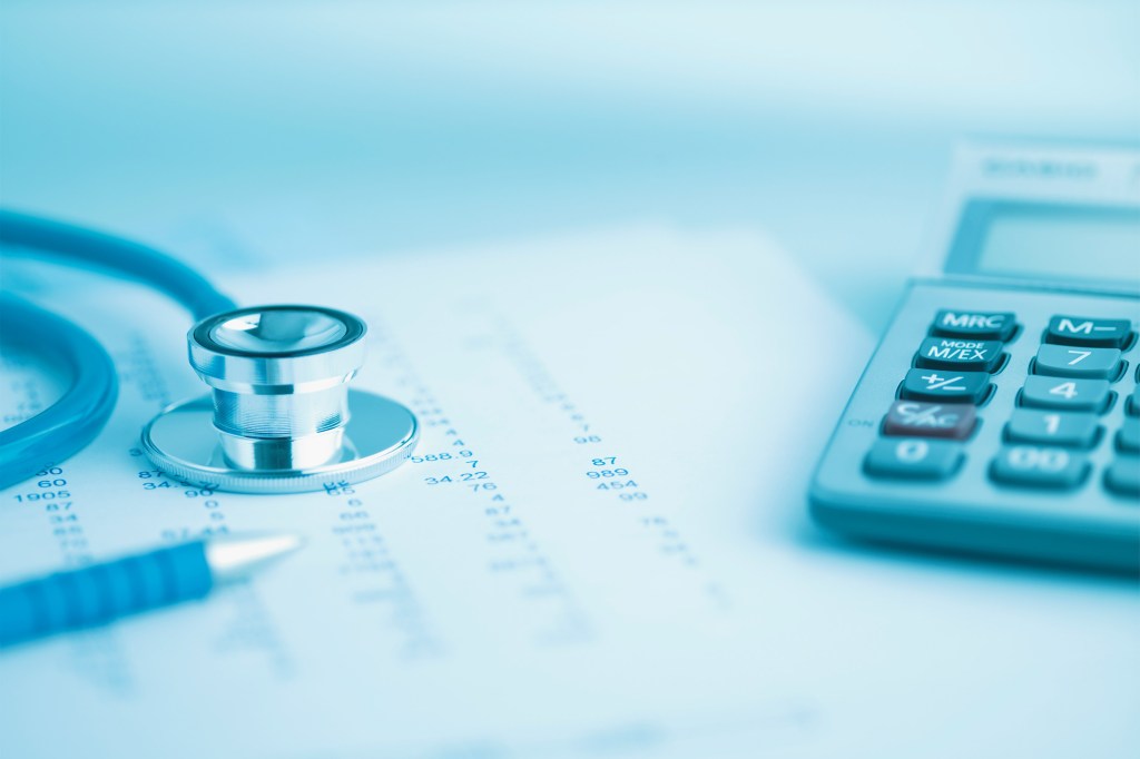 An image of a desk topped with a stethoscope, a medical paper, and a calculator.