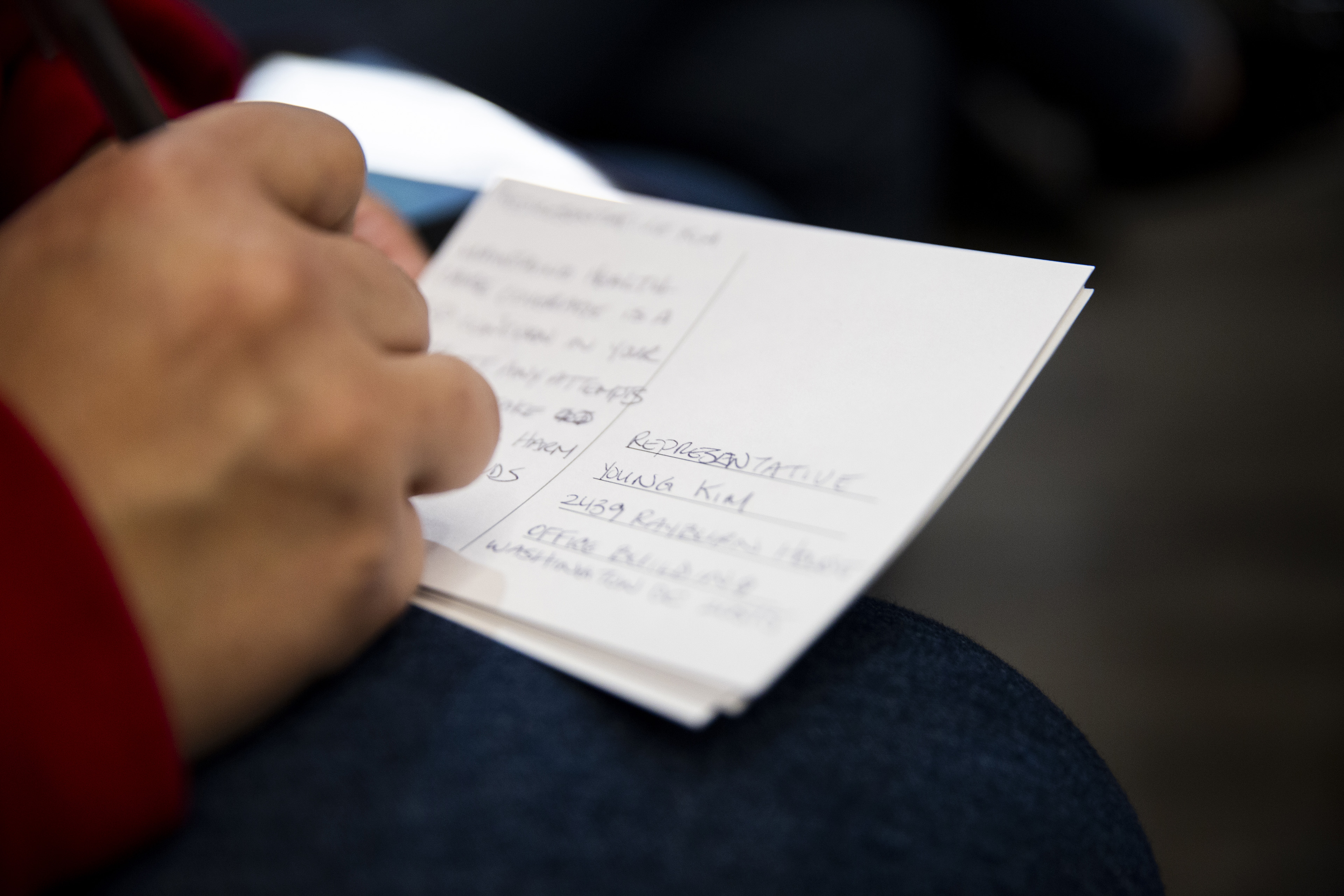 A woman writes a postcard.