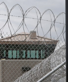A photo of a barbed wire fence seen in front of a guard tower.