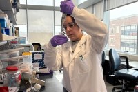 A photo of a woman in a lab coat using a pipette and flask.