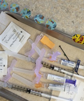 Alcohol pads, syringes, vaccines, and bandages lie on a tray at a pediatrician's office