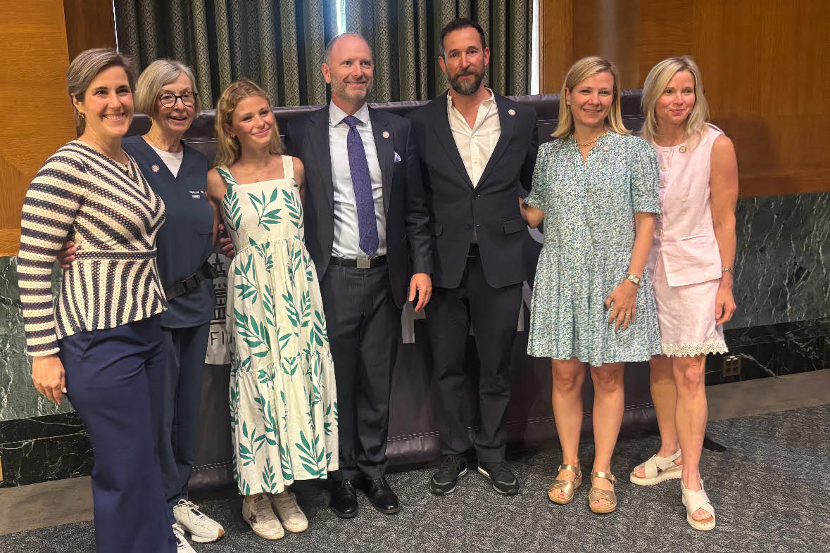 A group of five women and two men stand in a row together for a picture.