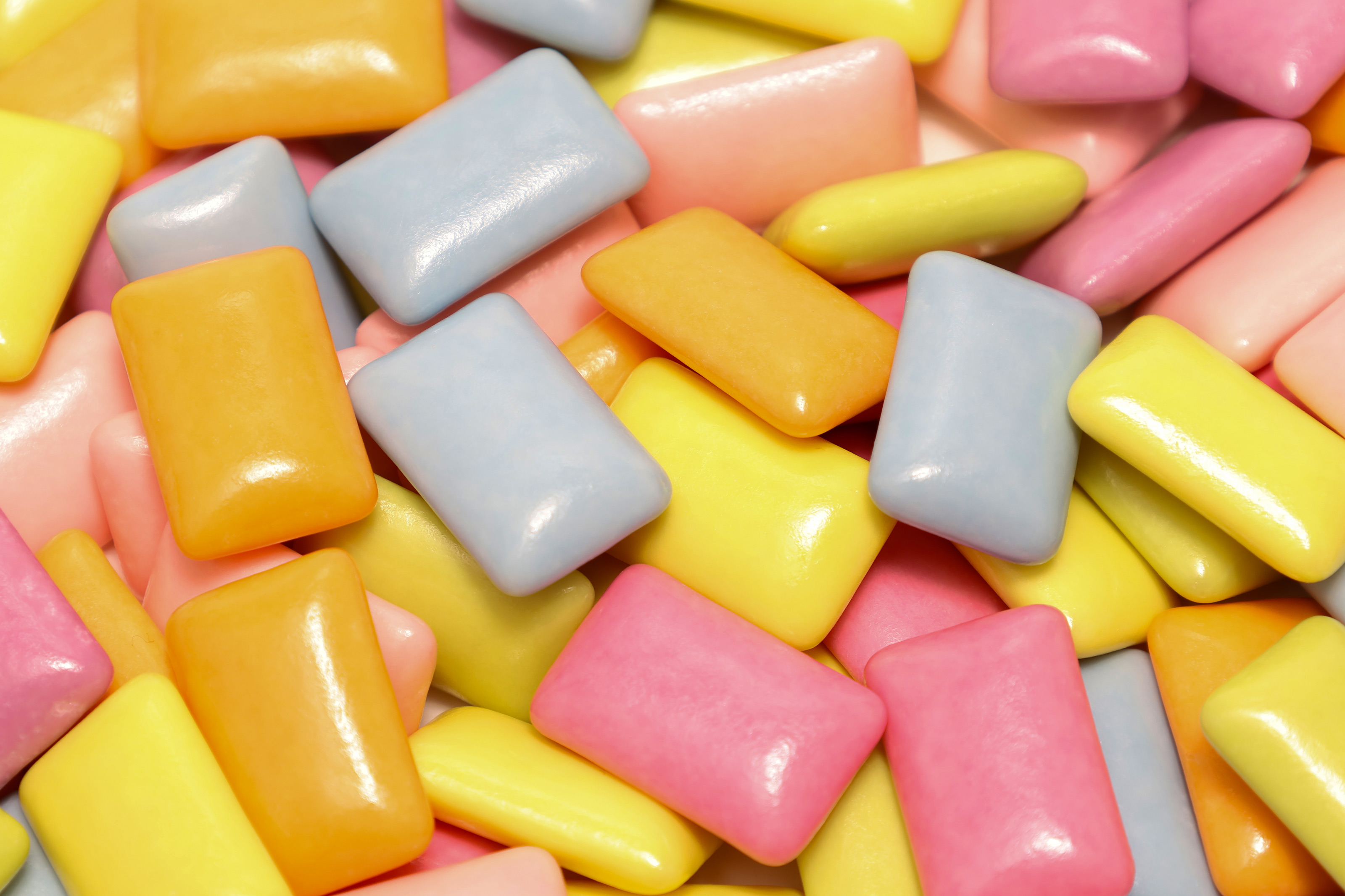 A photo of a pile of xylitol chewing gum tablets in a variety of colors.