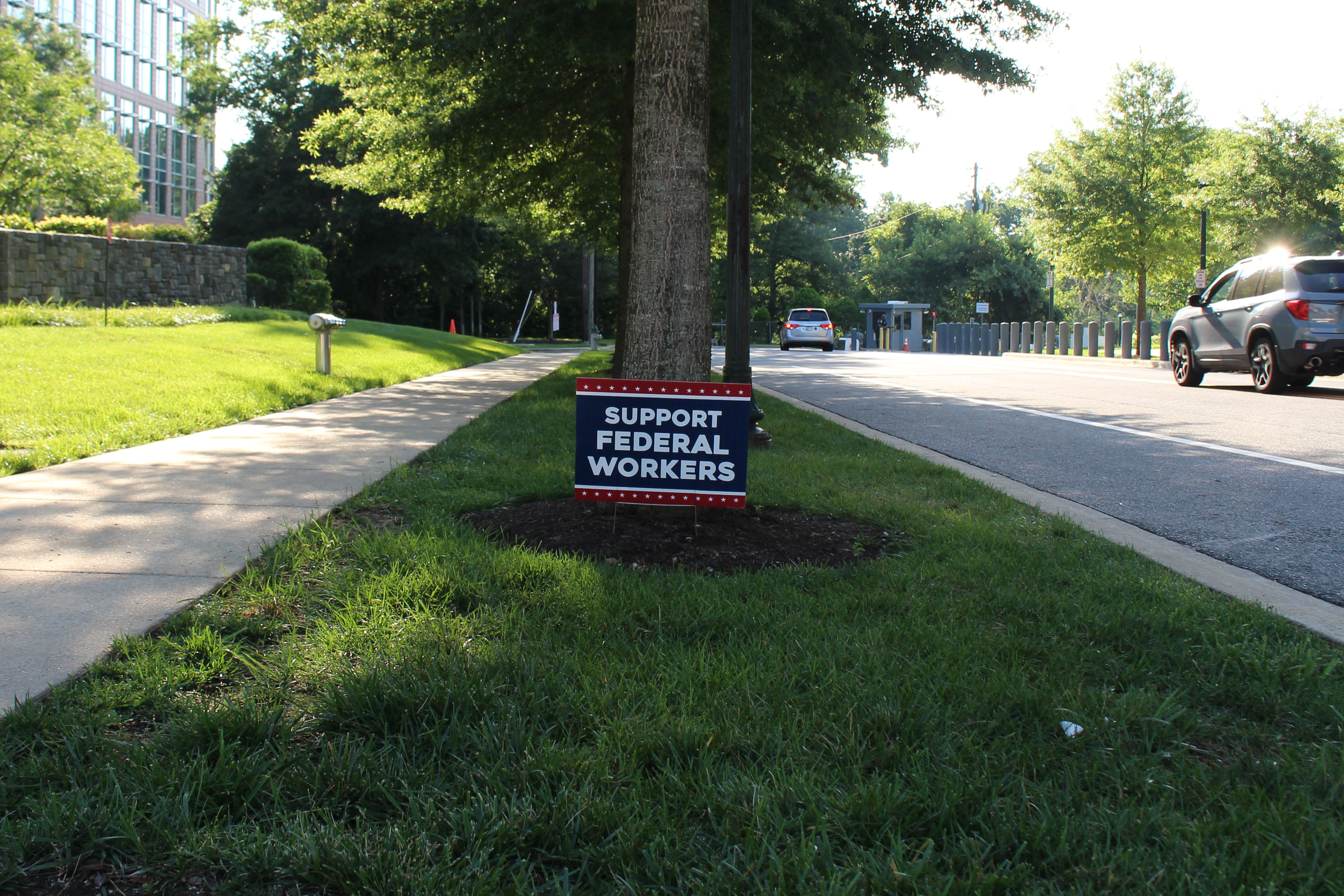 A lawn sign near a sidewalk reads, "support federal workers."