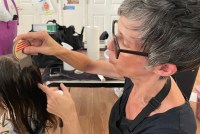 A photo of a woman using a lice comb on a young girl.